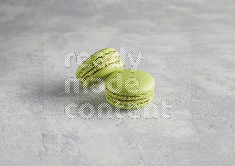 45º Shot of two Green Pistachio macarons  on white  marble background