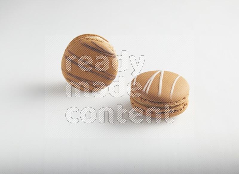 45º Shot of of two assorted Brown Irish Cream, and light brown  Almond Cream macarons on white background