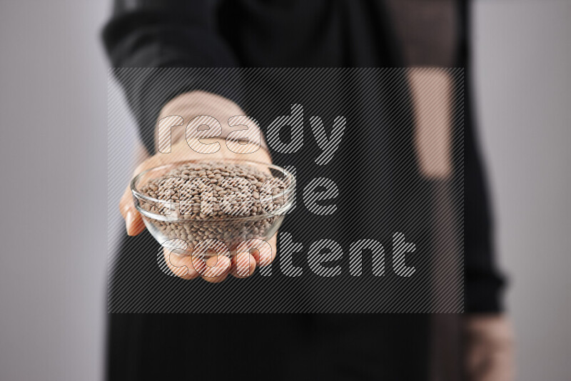 Woman in abaya holding different kinds of legumes in different positions
