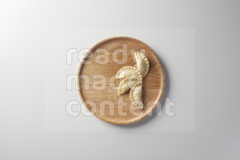 Four Sambosas on a wooden round plate on a white background