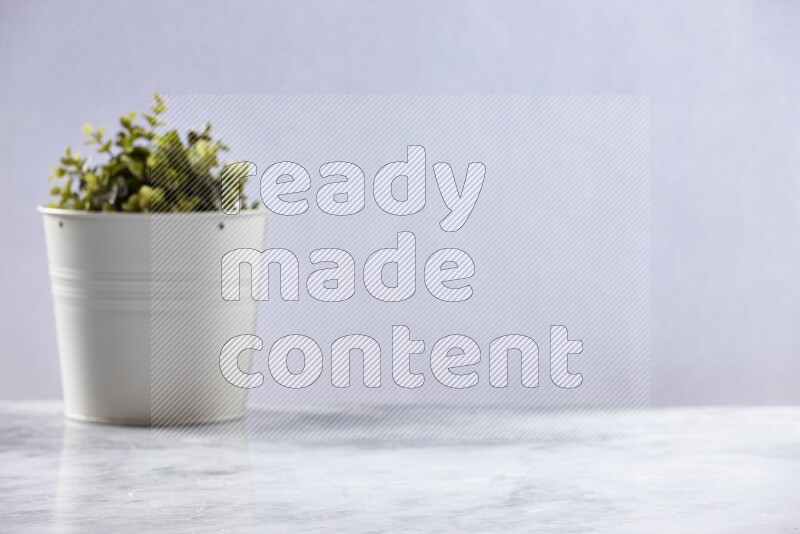 Artificial plant in white pot on grey marble background