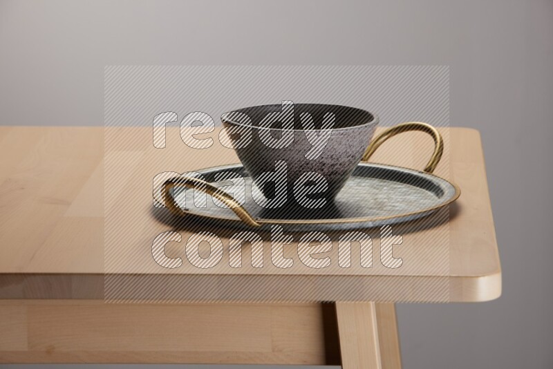 multicolored bowl placed on a rounded stainless steel tray with golden handels on the edge of wooden table