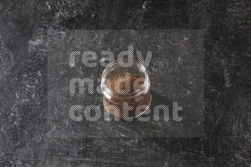 وعاء زجاجي ممتلئ ببودرة القرنفل على أرضية سوداء