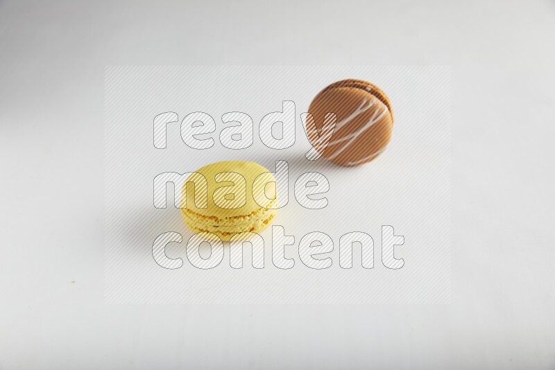 45º Shot of of two assorted Brown Irish Cream, and Yellow Lemon macarons on white background
