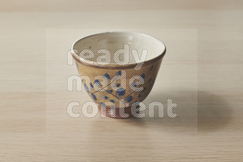 A decorative pottery bowl on light wooden background
