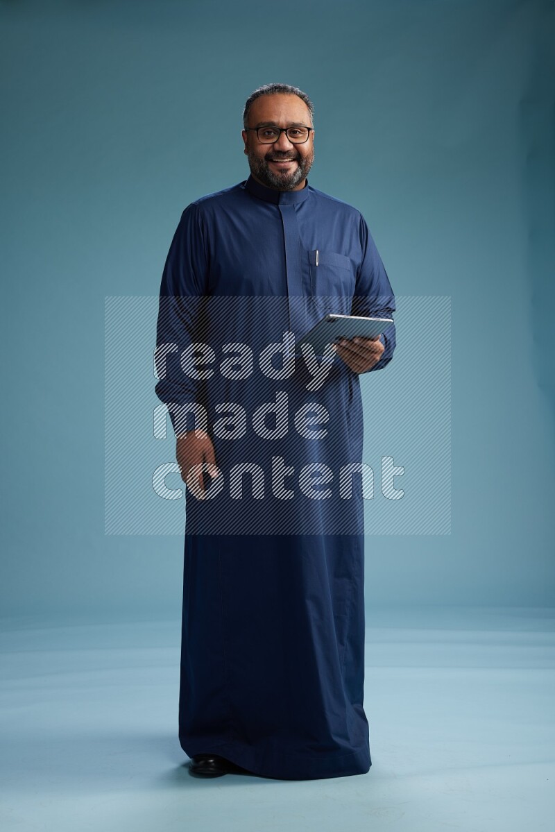 Saudi Man without shimag Standing working on tablet on blue background