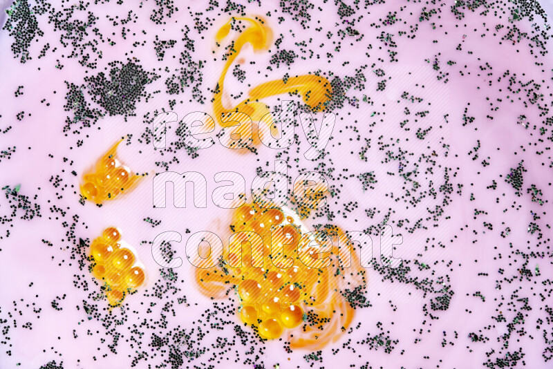 لقطة مقربة لبريق أخضر متلألئ منتشر على خلفية من اللون الأصفر والوردي في حركات دائرية
