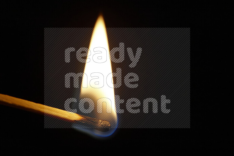 A burning matchstick isolated on dark backdrop