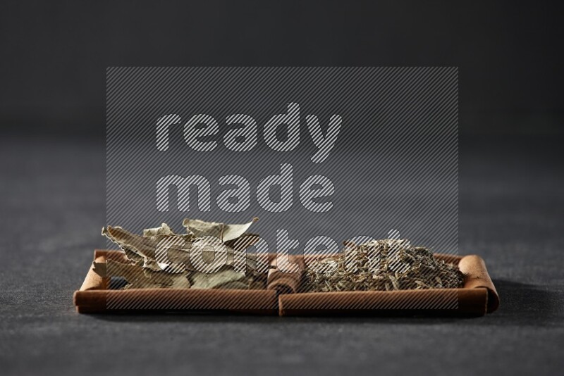 2 squares of cinnamon sticks full of cumin and bay laurel leaves on black flooring