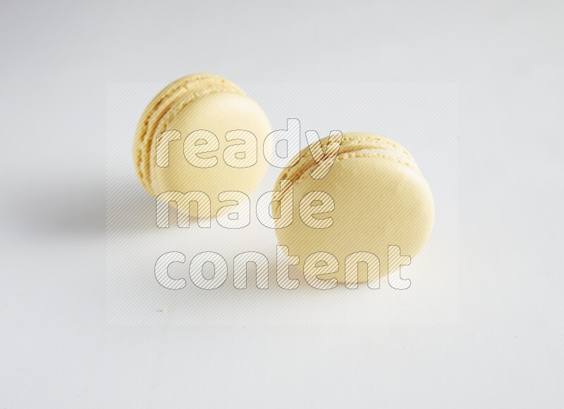 45º Shot of two Yellow Vanilla macarons on white background