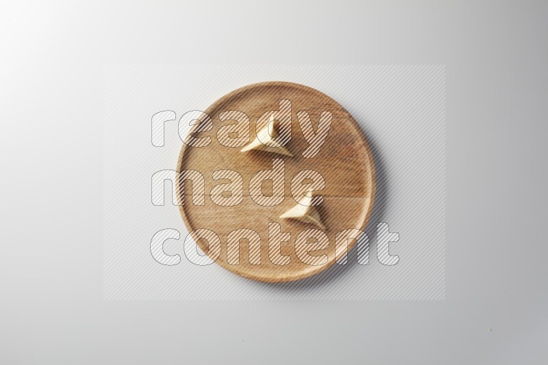 Two Sambosas on a wooden round plate on a white background