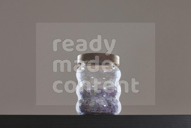 Sequins in a glass jar on black background