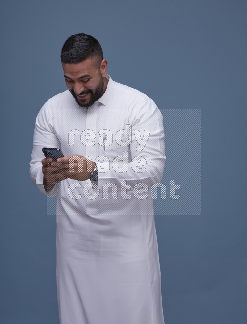 A man Texting on Blue Background wearing Saudi Thob