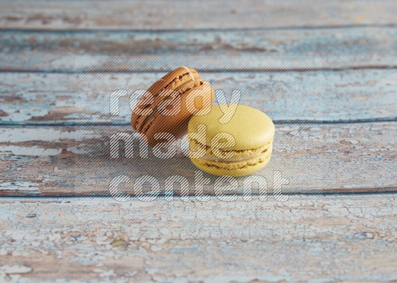 45º Shot of of two assorted Brown Irish Cream, and Yellow Lime macarons on light blue background