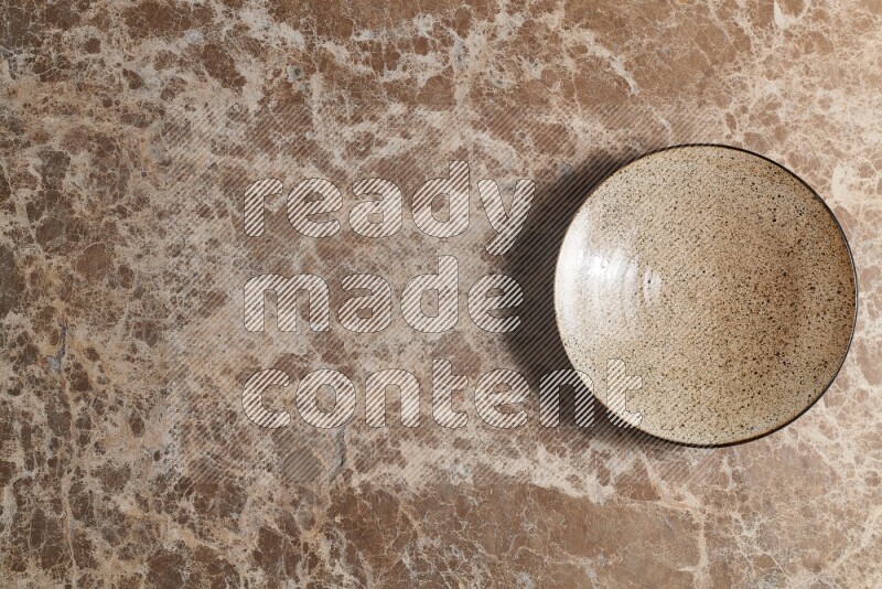 A beige pottery plate on beige marble background
