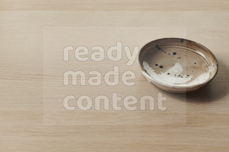 A multicolored pottery plate on light wooden background