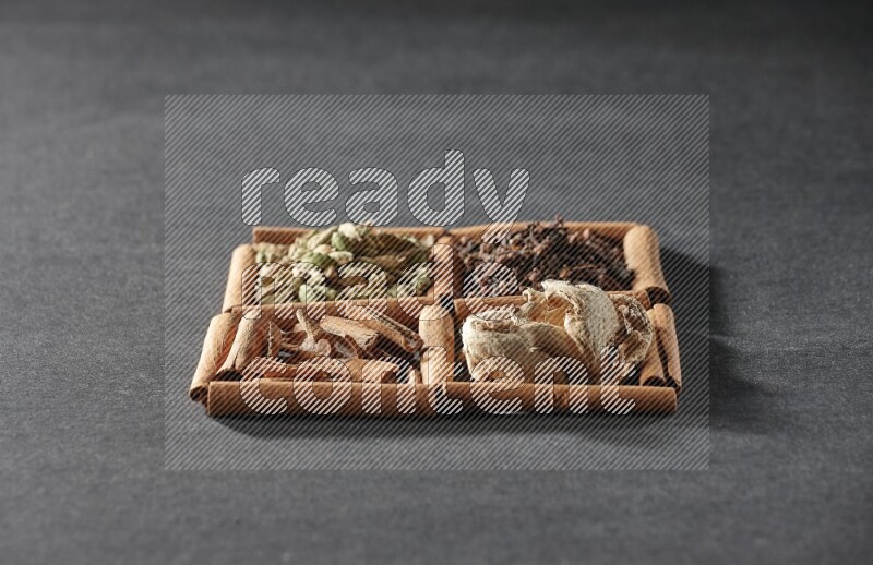 4 squares of cinnamon sticks full of cinnamon, cardamom, cloves and dried ginger on black flooring