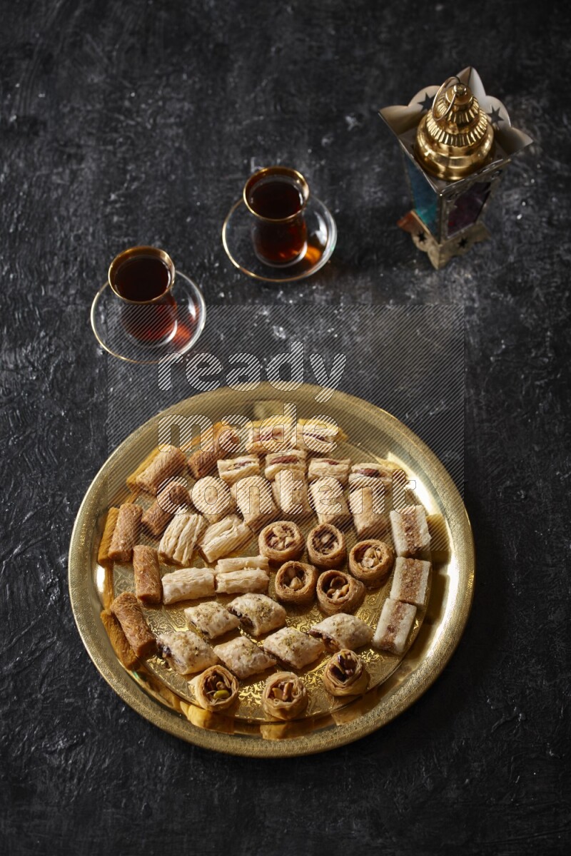 Oriental desserts with tea and a metal lantern in a dark setup