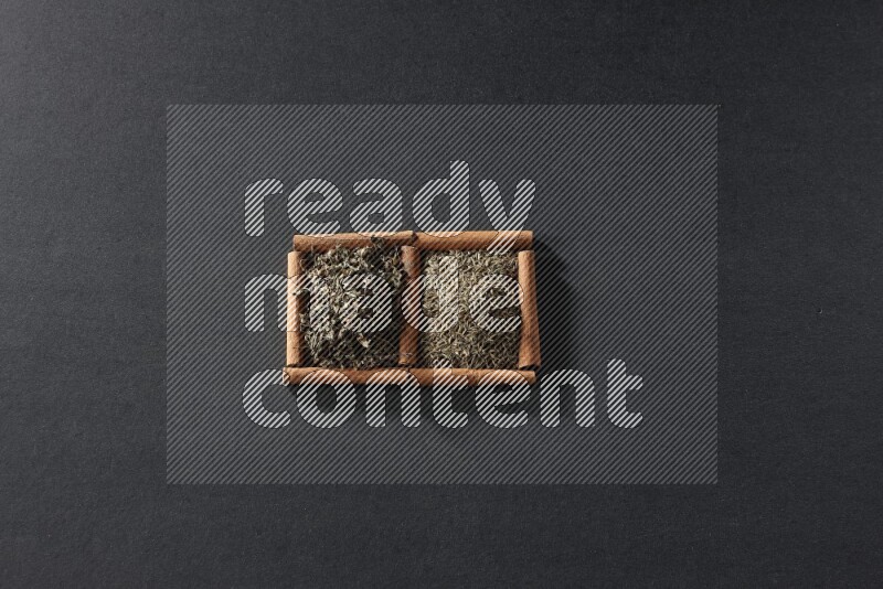 2 squares of cinnamon sticks full of cumin and dried basil on black flooring