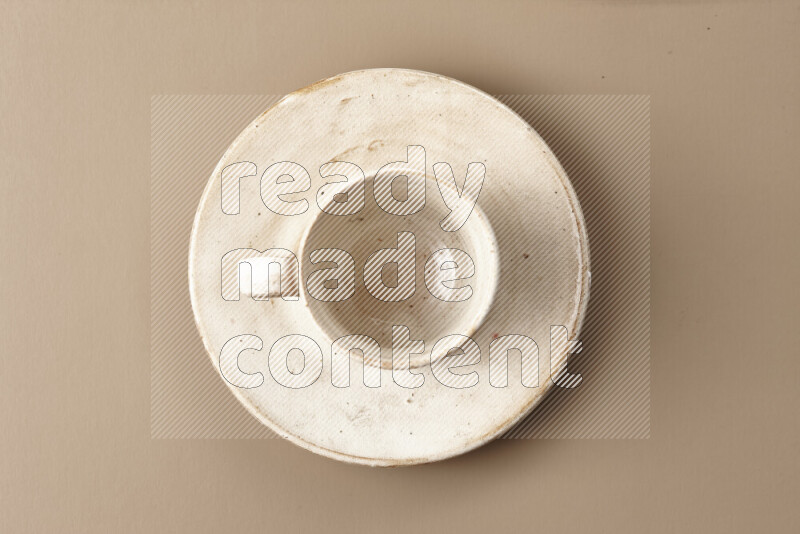 A beige pottery cup full of roasted coffee beans on beige background