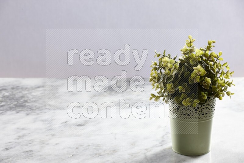 Artificial plant in green decorative pot on grey marble background