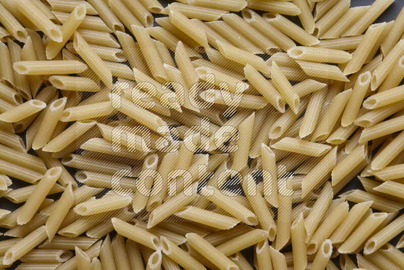 Mini penne pasta on grey background