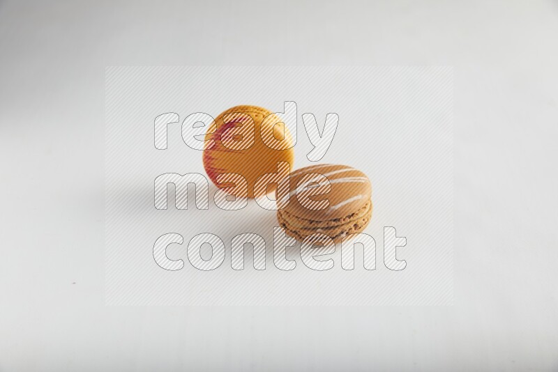 45º Shot of of two assorted Brown Irish Cream, and Orange Exotic macarons on white background