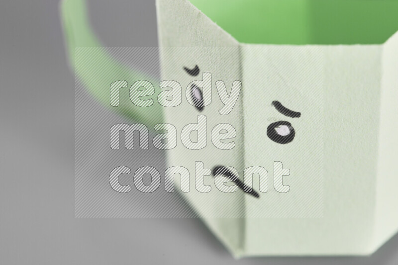 Origami cup on grey background