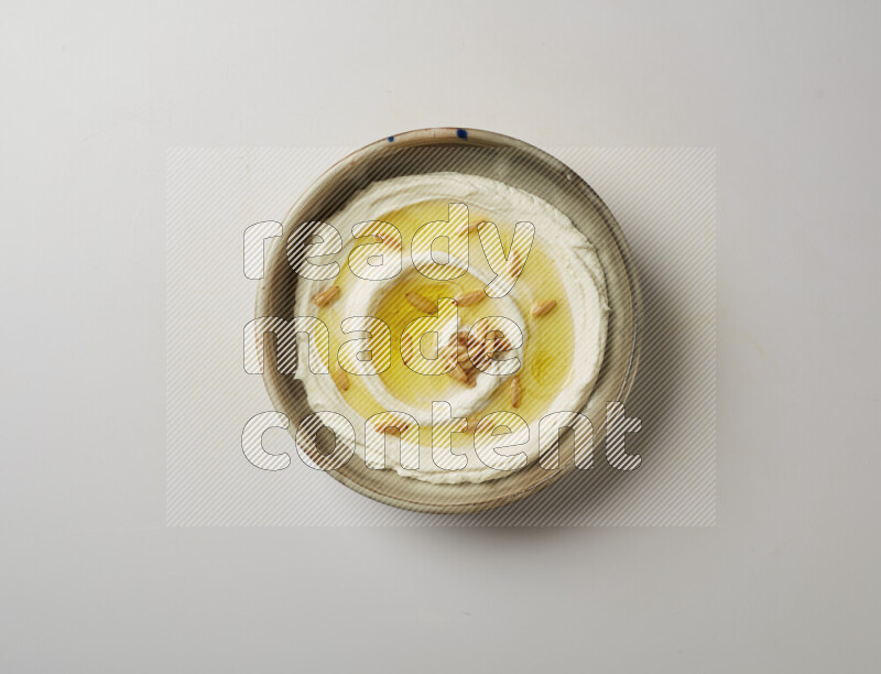 Lebnah garnished with pine nuts in a grey pottery plate on a white background