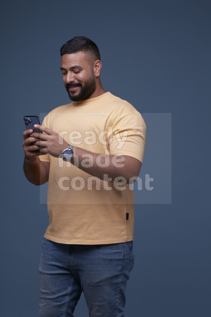 A man Texting on his phone in Blue Background wearing Orange T-shirt