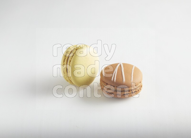 45º Shot of of two assorted Brown Irish Cream, and Yellow Lime macarons on white background