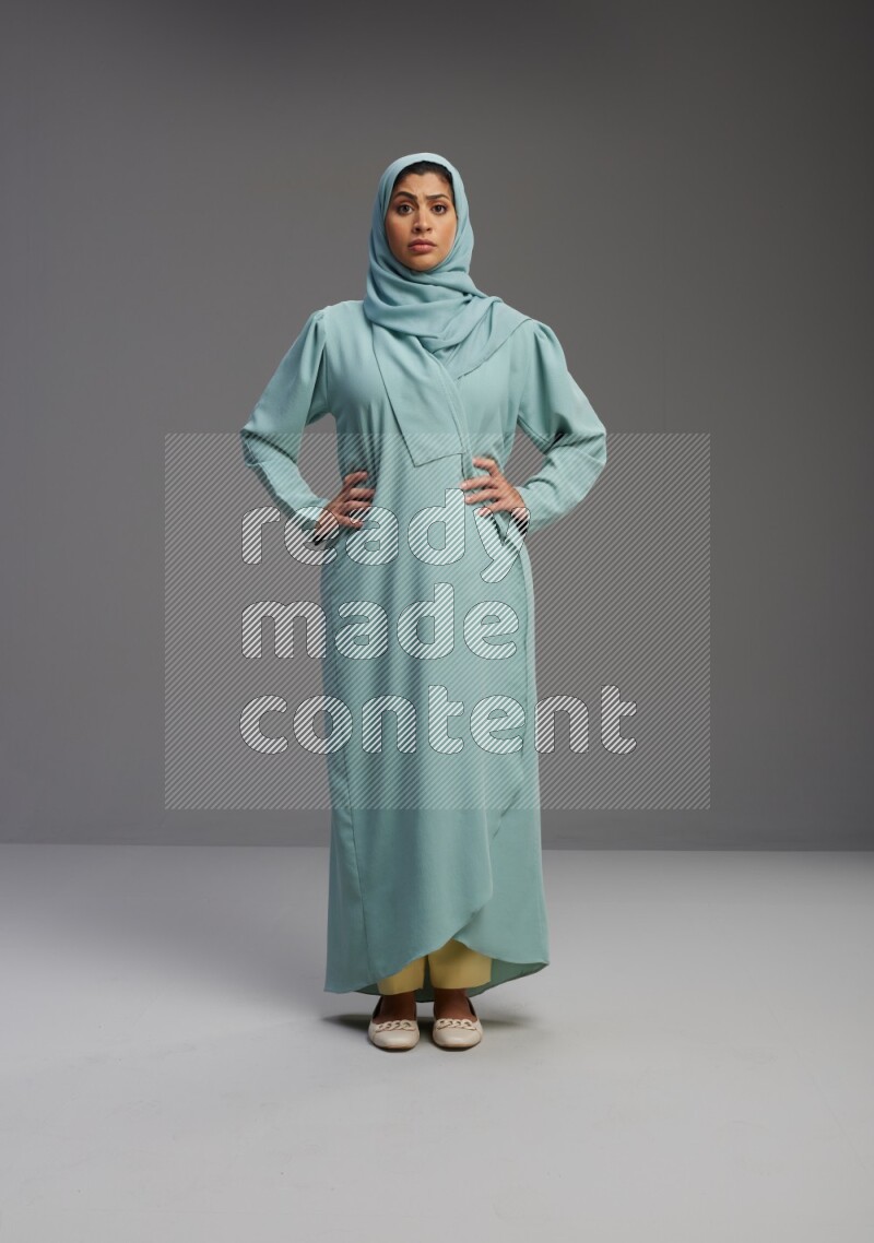 Saudi Woman wearing Abaya standing interacting with the camera on Gray background