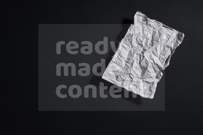 Crumpled notebook sheet on black background