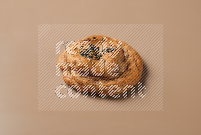 a whole Hasawi cookie with grains on a brown background