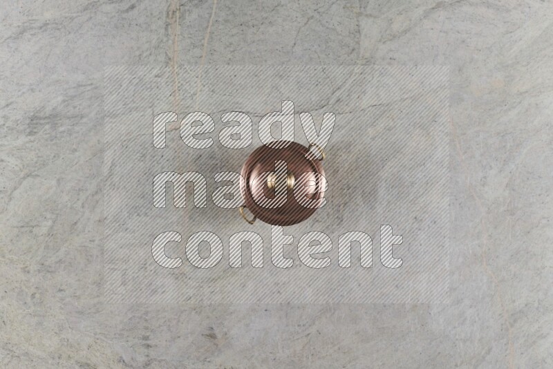 A small copper pot on grey marble background