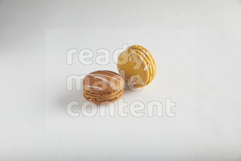 45º Shot of of two assorted Brown Irish Cream, and Yellow Piña Colada macarons on white background