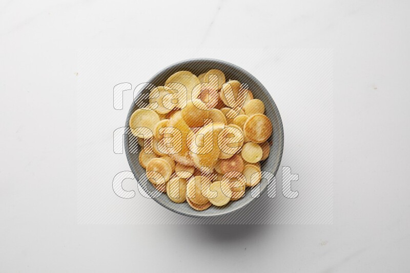 Top-view shot of orange candy cereal pancakes in a round bowl on white background