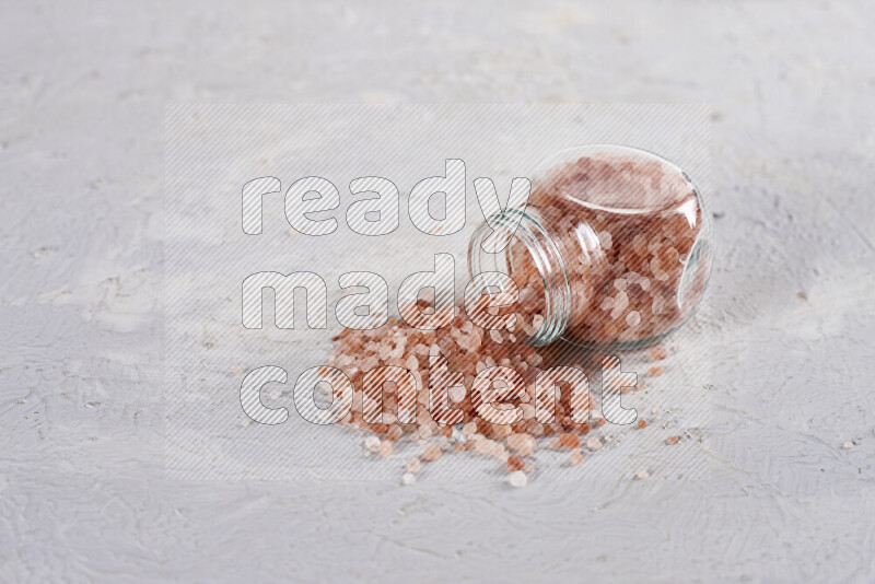 A glass jar full of coarse himalayan salt crystals on white background
