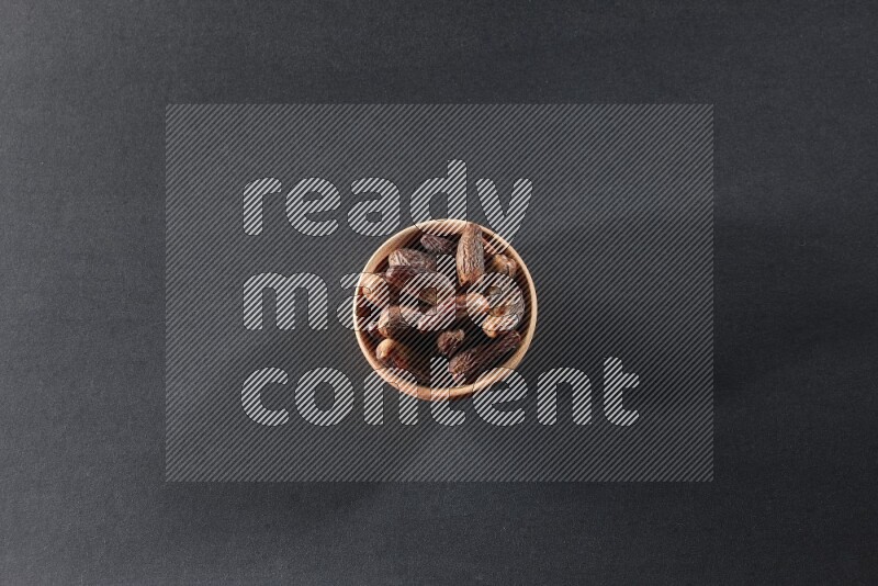 A wooden bowl full of dried dates on a black background in different angles