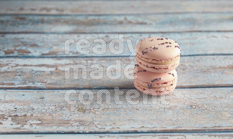 45º Shot of two pink orange blossom macarons on light blue wooden background