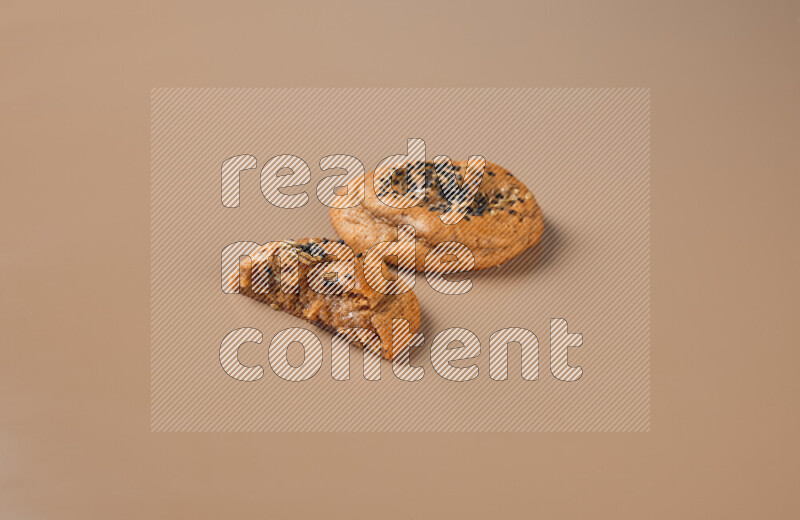 a Hasawi cookie field of date and herbs with another one cut in half on a brown background