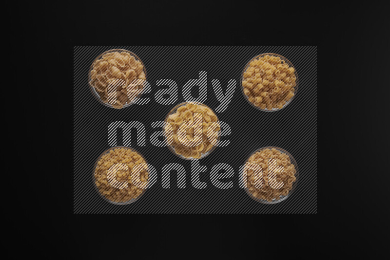 أنواع مختلفة من المعكرونة في أوعية زجاجية علي خلفية سوداء