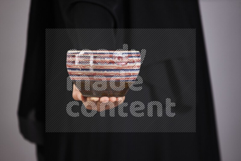 A woman in black abaya holding different pottery essentials in different positions