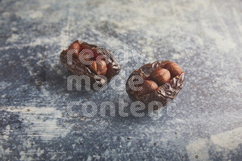 two hazelnuts stuffed madjoul dates on a rustic blue background