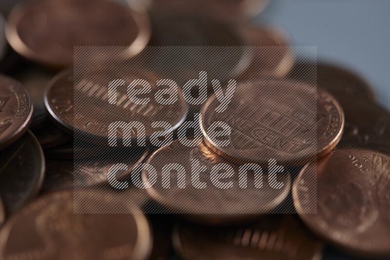 صورة مقربة لعملات معدنية متناثرة بقيمة سنت أمريكي على خلفية رمادية