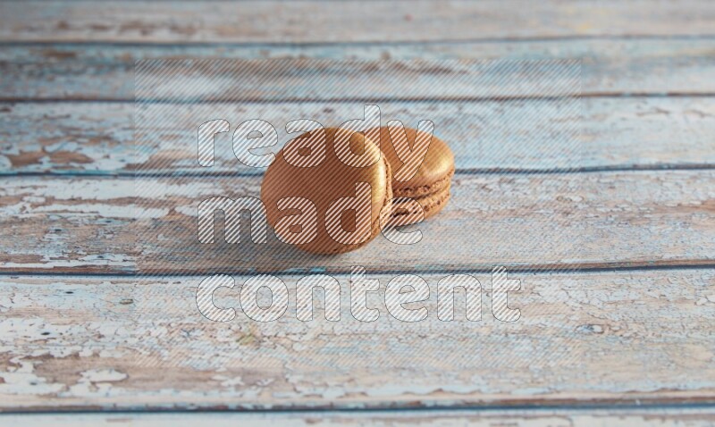 45º Shot of two Brown Coffee macarons on light blue wooden background