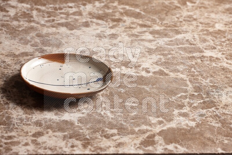 A multicolored pottery plate on beige marble background