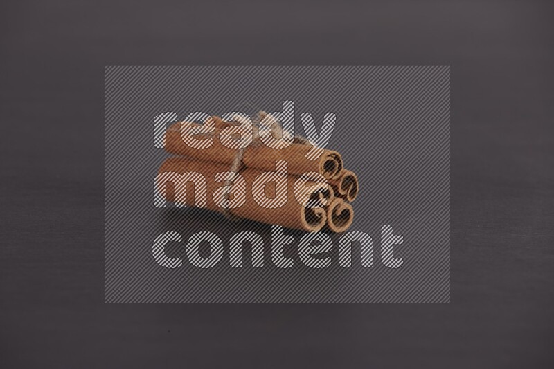 4 أعواد من القرفة مربوطة علي خلفية سوداء