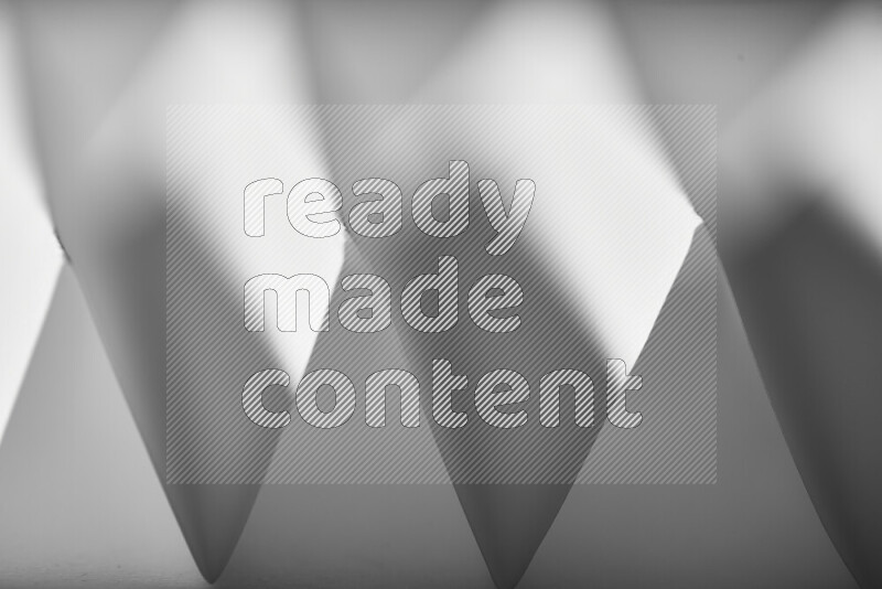 صورة مجردة مقربة تظهر طيات ورقية هندسية حادة بتدرجات اللون الرمادي