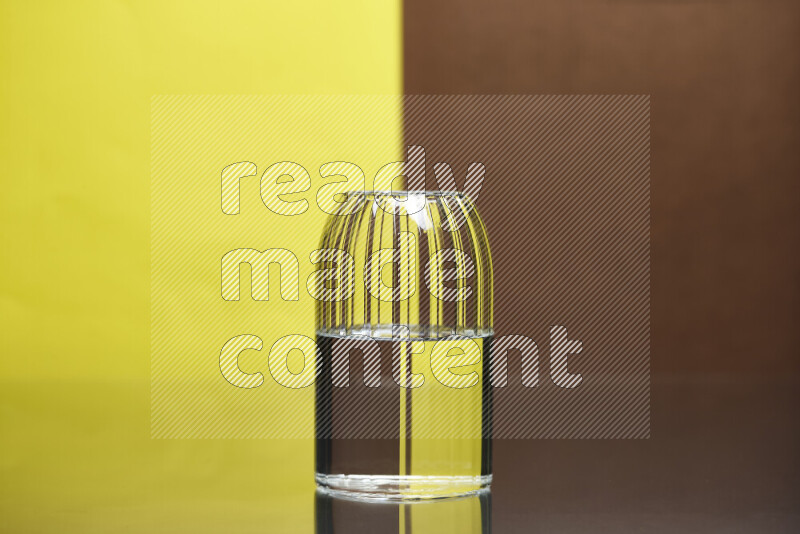 The image features a clear glassware filled with water, set against yellow and brown background